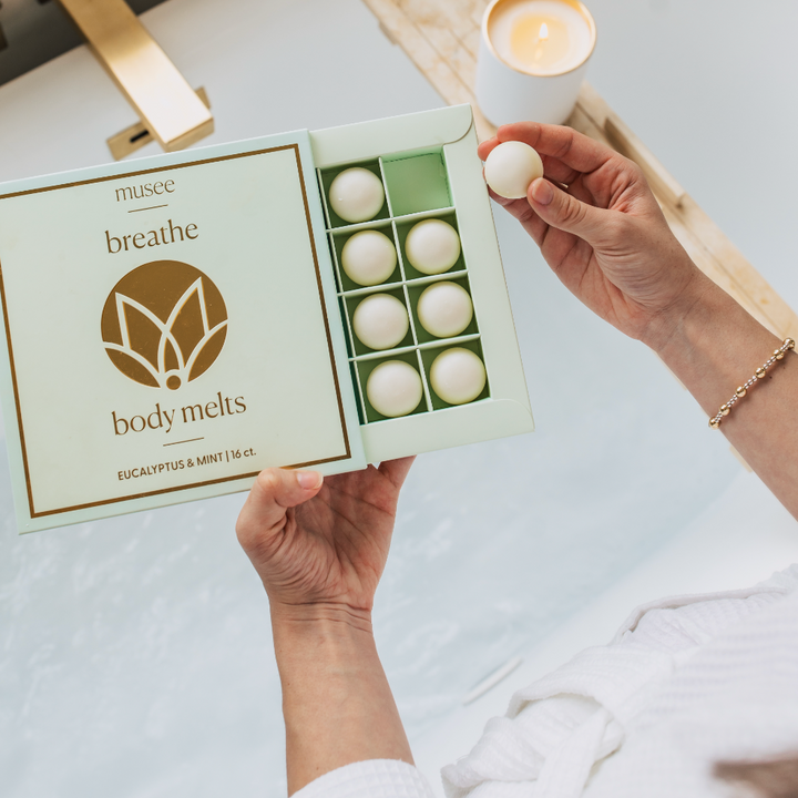 Muse breathe body melts packaging with melts and a lit candle on a white surface