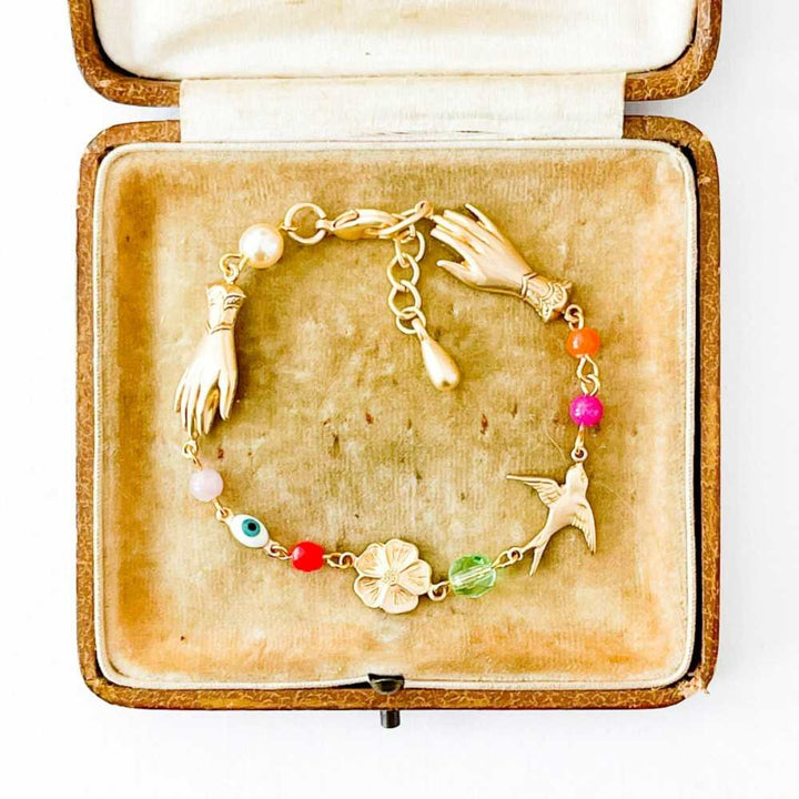 Nest Pretty Things | Bracelet | A gold bracelet with charms and beads, Displayed in a vintage box.