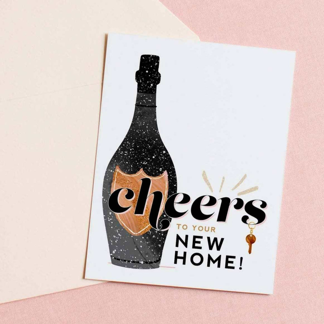 A simple white card with a champagne bottle illustration and text that reads "cheers to your new home!".