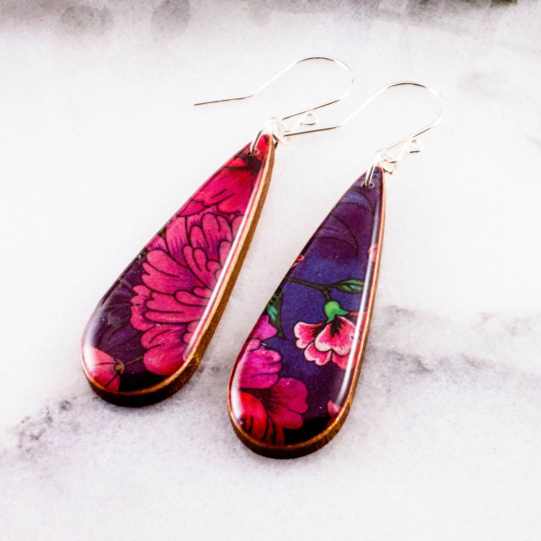Teardrop-shaped earrings with floral design on a marble surface