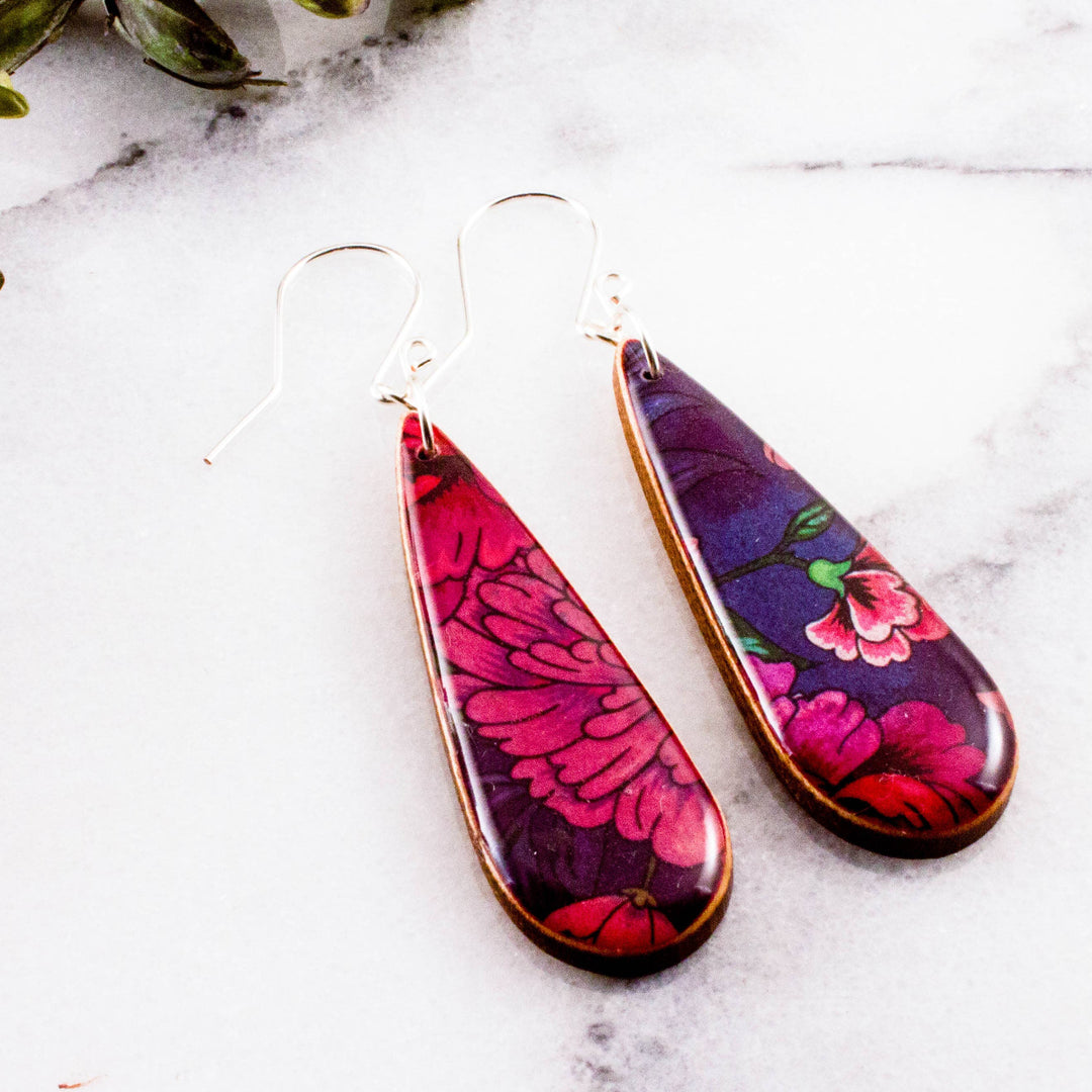 Teardrop-shaped earrings with floral design on a marble surface
