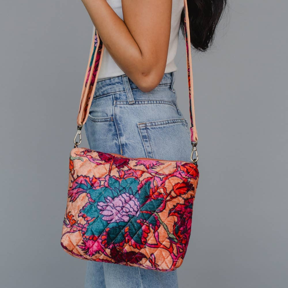 Person holding a colorful floral-patterned bag against a gray background