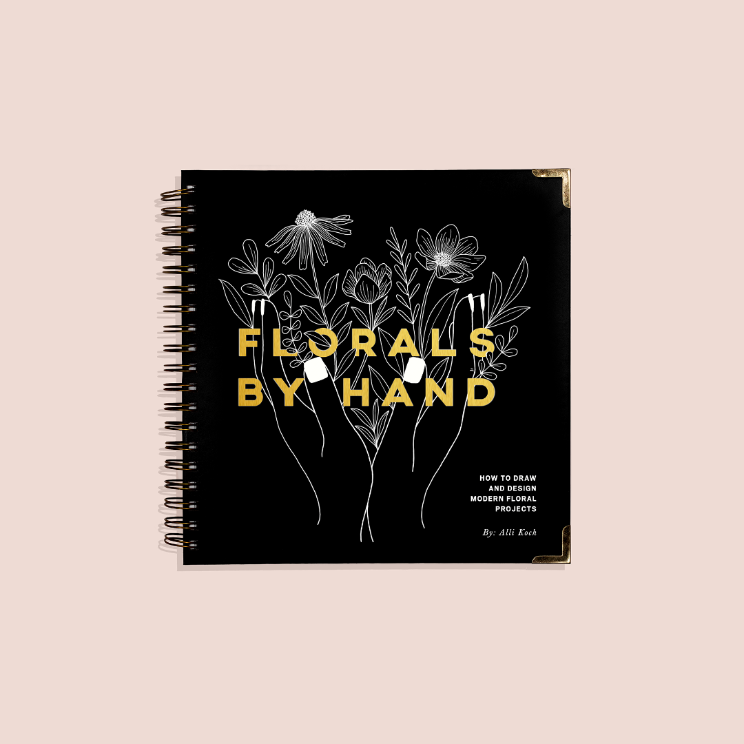 Book titled 'Florals by Hand' with floral illustrations on a black cover against a beige background