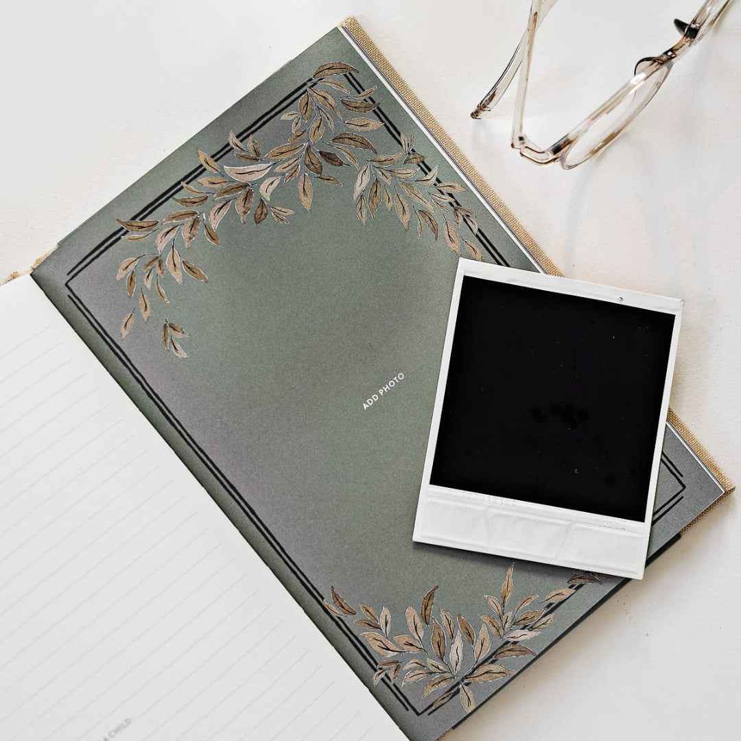 Gray notebook with floral design and a black square photo on a white surface