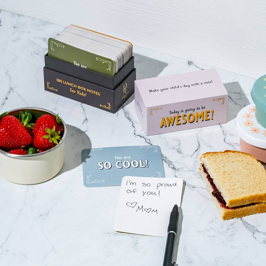 Stack of cards, a pen, and a small container with strawberries on a light surface.