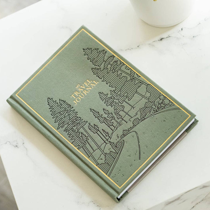 Green book with engraved design on a marble surface