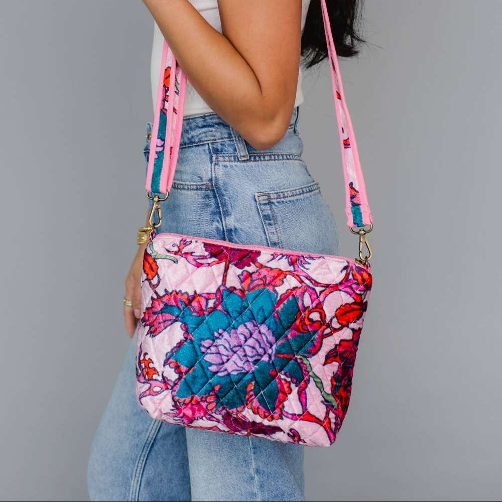 Panache Apparel Co. | Woman holding a colorful floral-patterned crossbody bag against a gray background