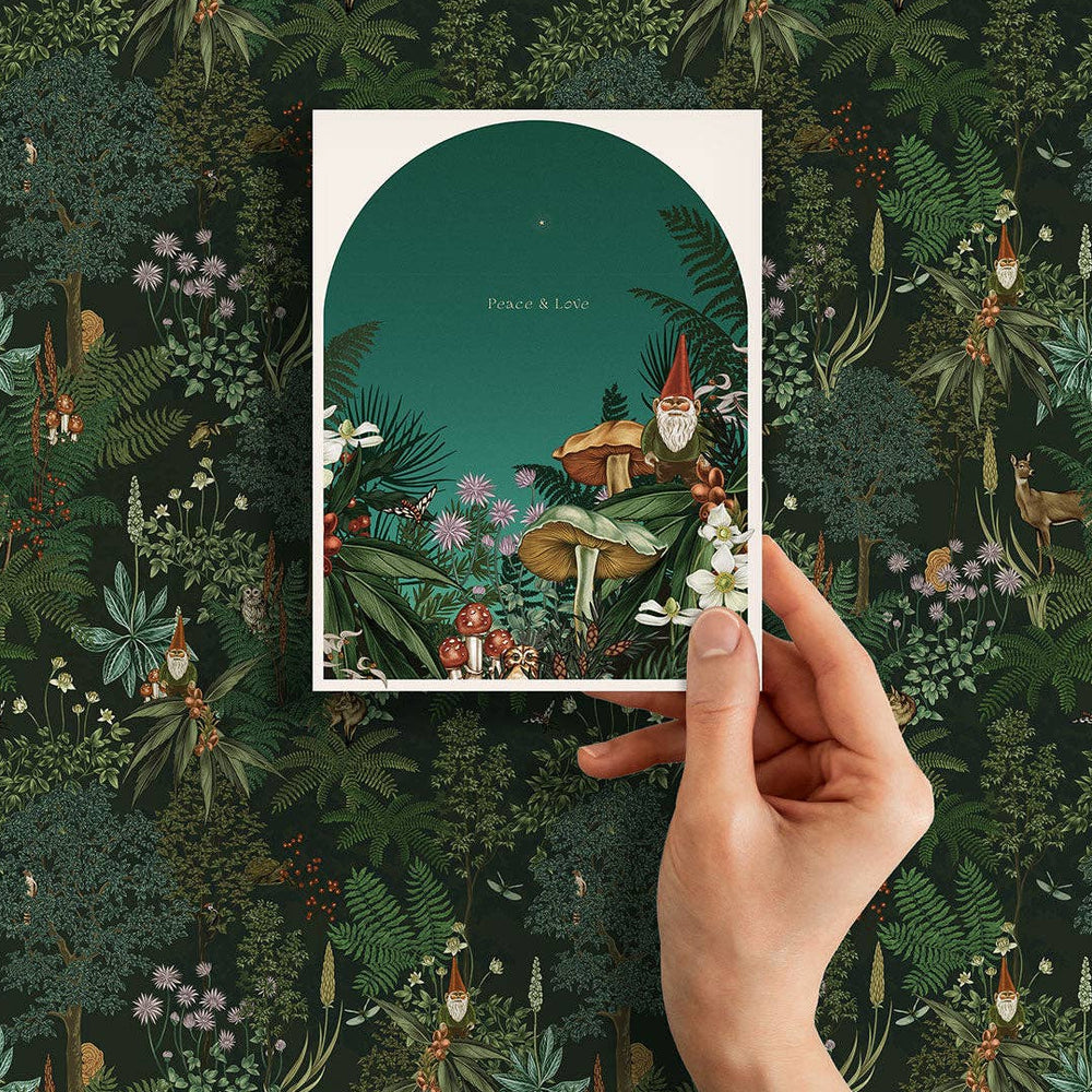 Hand holding a card with a forest design against a matching patterned background