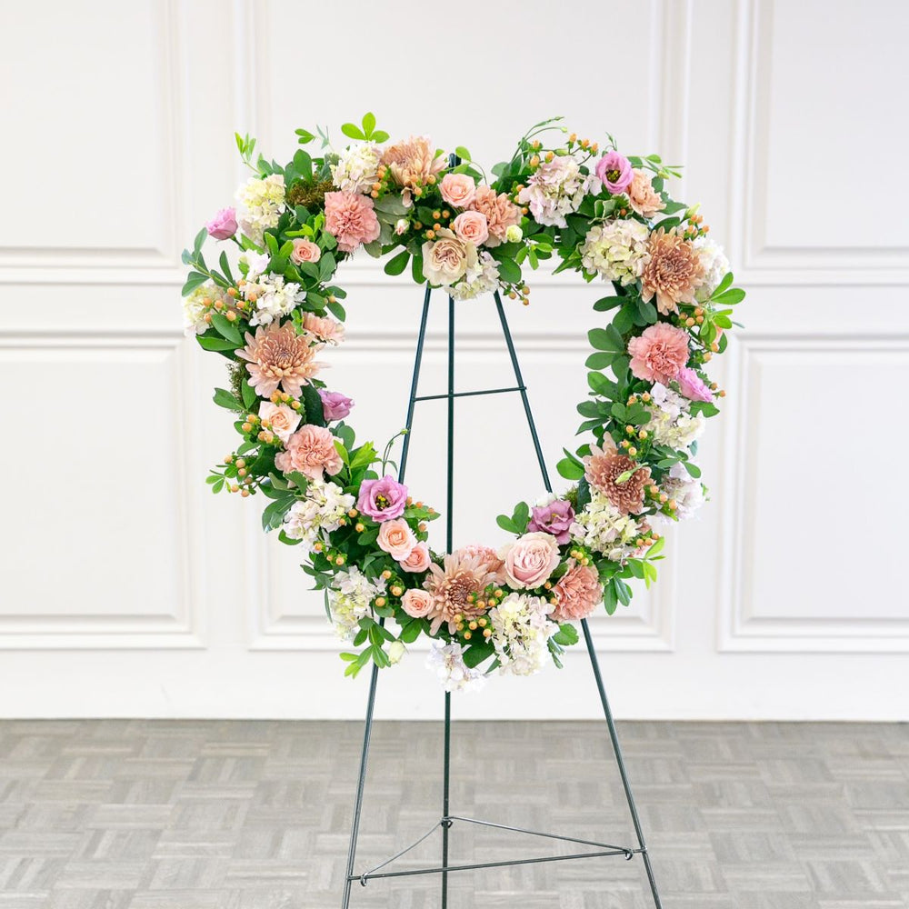 Floral wreath on a stand against a white wall