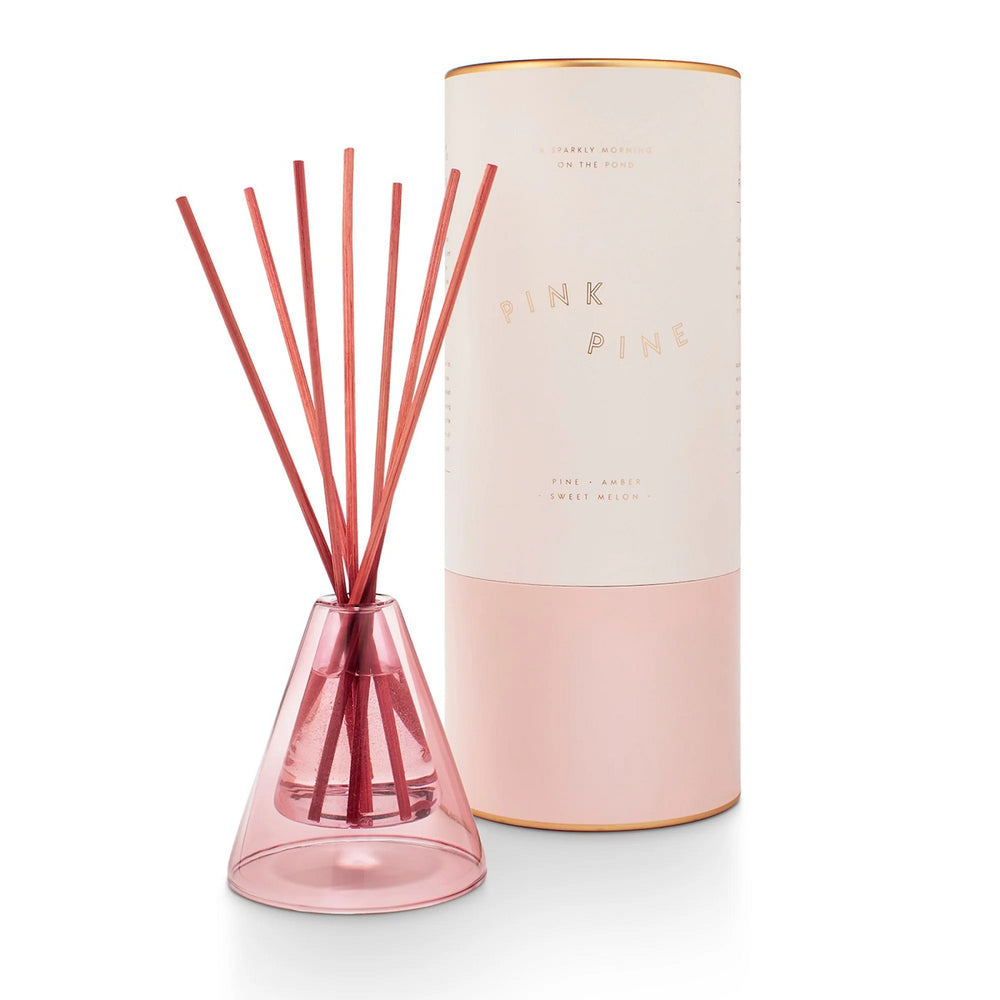 Winsome Diffuser | Pink Pine, pine, amber, and sweet melon scented. A light pink tapered glass diffuser with the scent carrying stick sticking out.