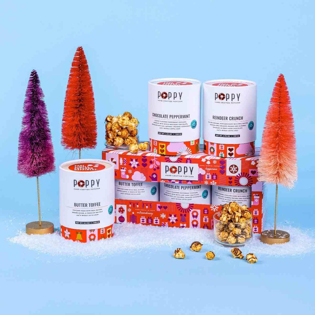 Poppy Hand-Crafted Popcorn | Holiday Cylinder Trio Popcorn | Holiday themed photo with reds and purples. Butter Toffee, Chocolate Peppermint, Reindeer Crunch.