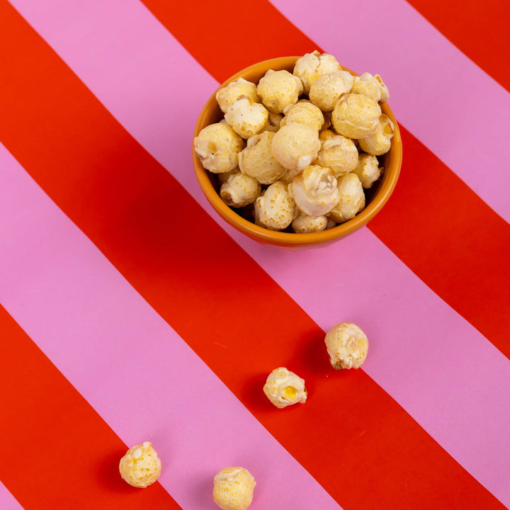 Popcorn in a bowl on a red and pink striped background