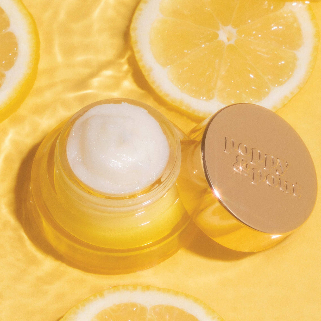 Skincare product jar with lid on a yellow background with lemon slices