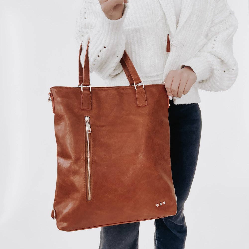 Close up on the brown vegan leather tote bag that has a top zipper and side pocket.