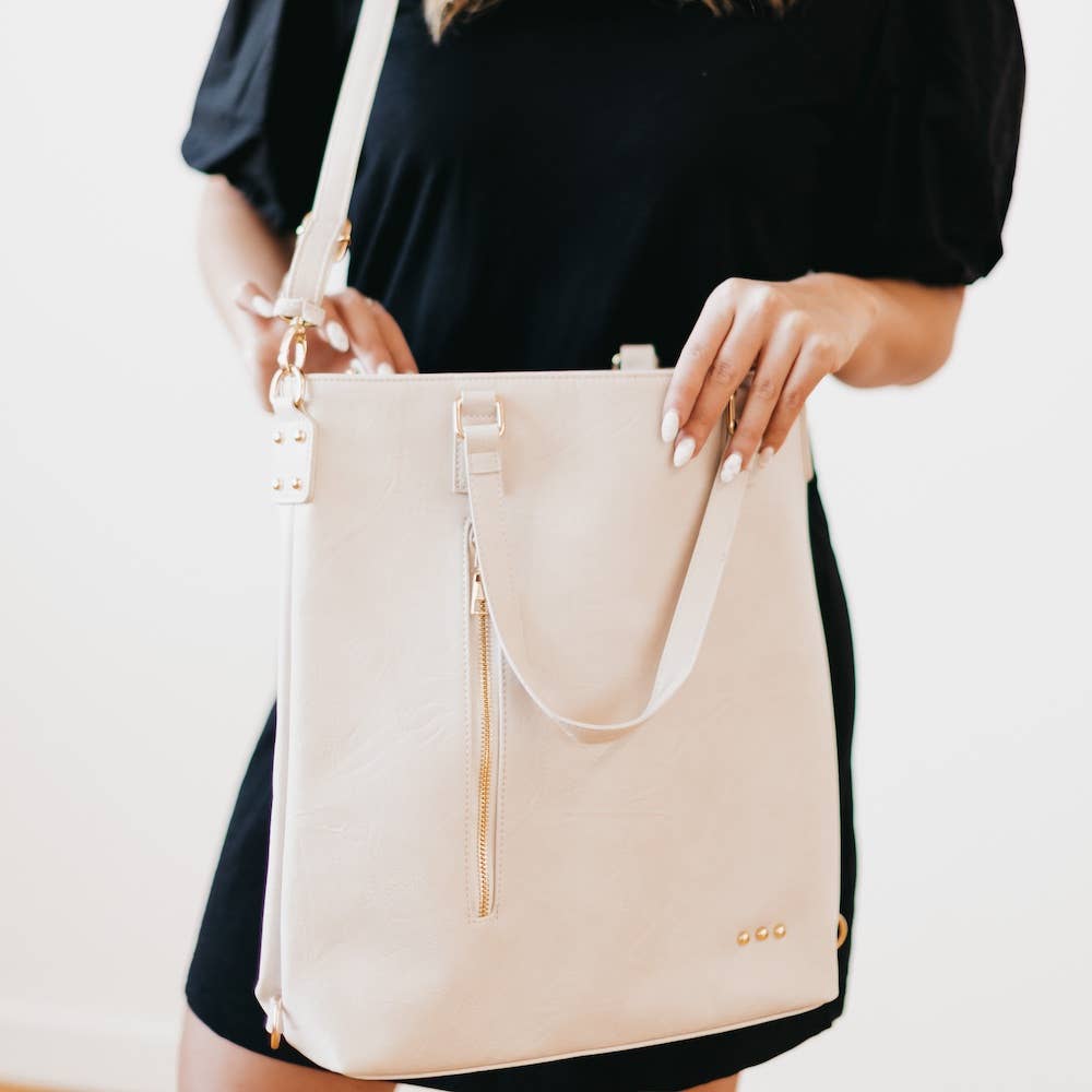 Close up on the cream tote bag showing the handles, shoulder strap, and side zipper.