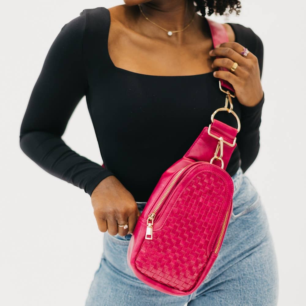 A pink crossbody bag with a woven design and gold hardware.