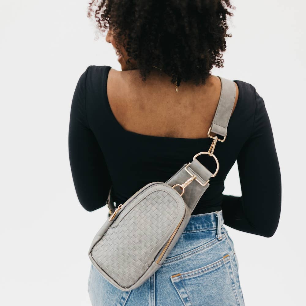 A gray vegan leather crossbody bag with a woven design.