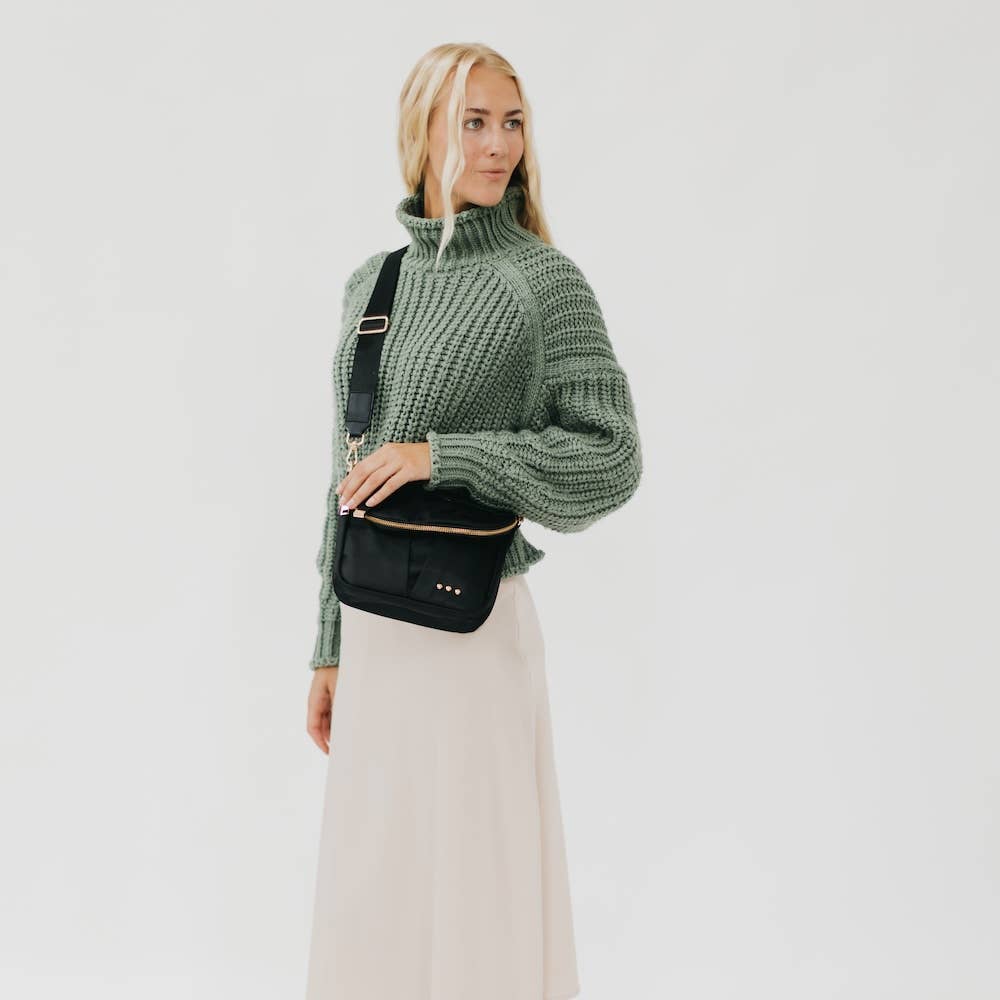 Pretty Simple | Tilly Crossbody Bag | Black with gold accents on a model who is wearing green.
