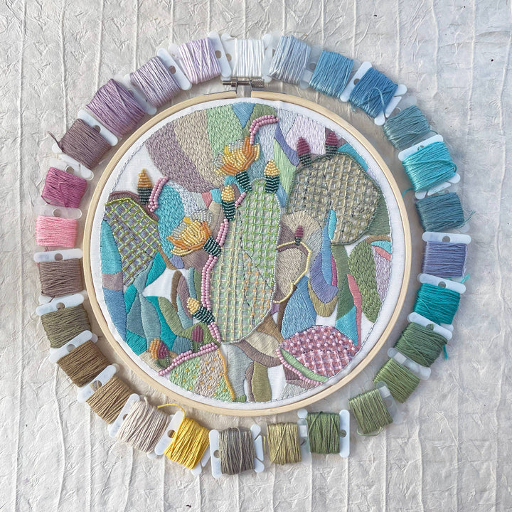 Embroidery hoop with colorful embroidered design on a textured white background