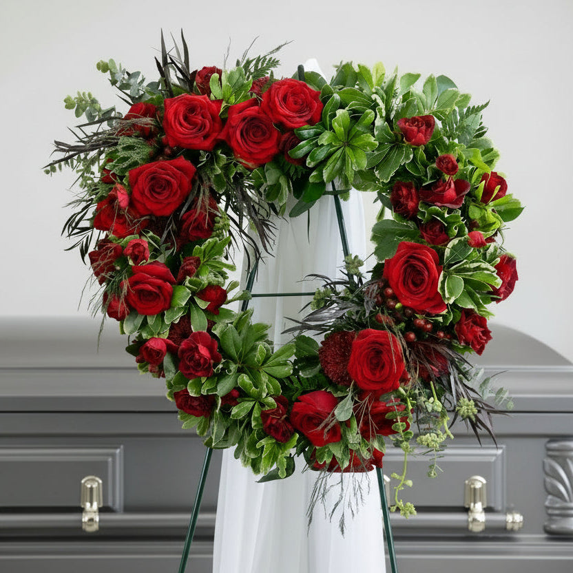 Heart-shaped arrangement of red roses and greenery.