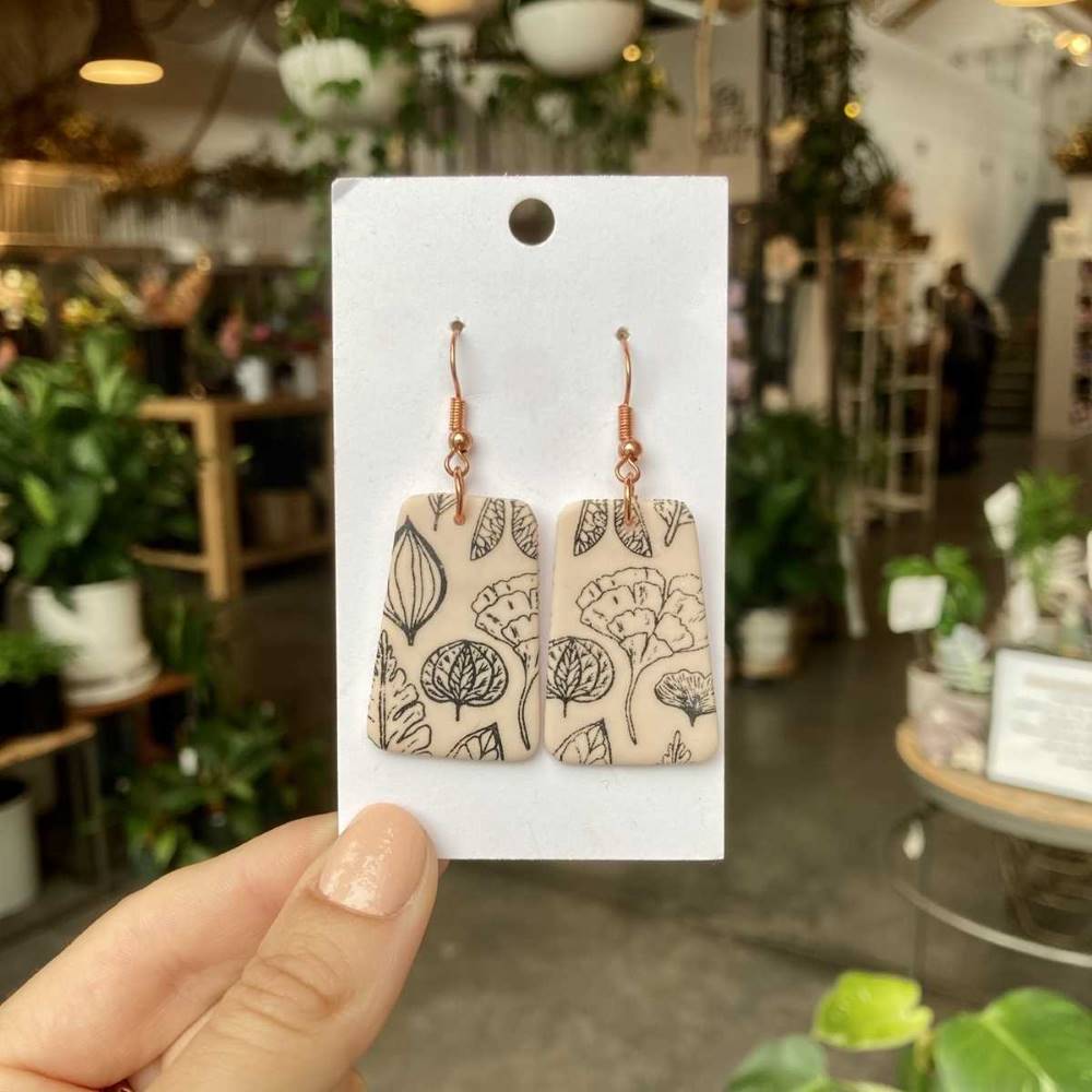 Rivergirl Curiosities | Plant Print Polymer Clay Earrings | A cream colored earring with a black fineline plant pattern.