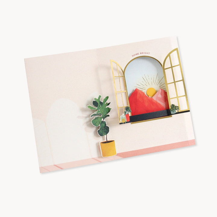 Shine Bright | UWP Luxe | Greeting card interior, an open window that opens to mountains and a sun. A pop up fiddle leaf fig plant is next to the open window. Text reads "Shine Bright"