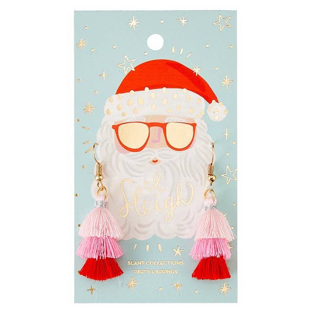 Slant | I Sleigh Earrings | A dangling pair of earrings with pink and red frills. The packaging is a Santa Clause backing.