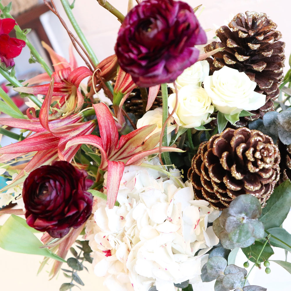 Snow Kissed | Close up on the hydrangea, lilies, pinecones, ranunculus, and eucalyptus.