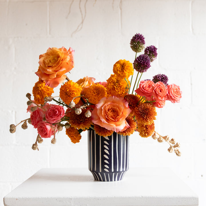 Colorful flower arrangement in a black and white vase on a white surface with a light gray background