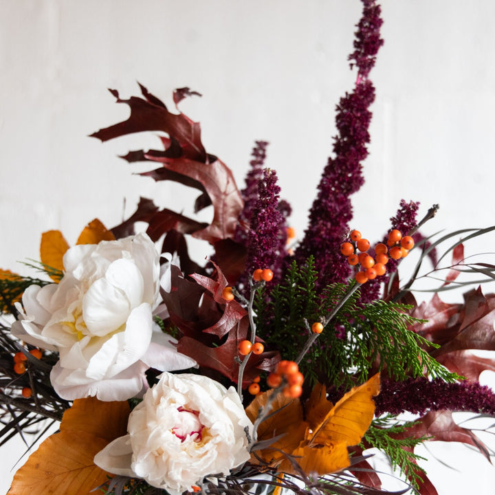 Autumnal flower arrangement with white flowers, purple and orange leaves on a white background