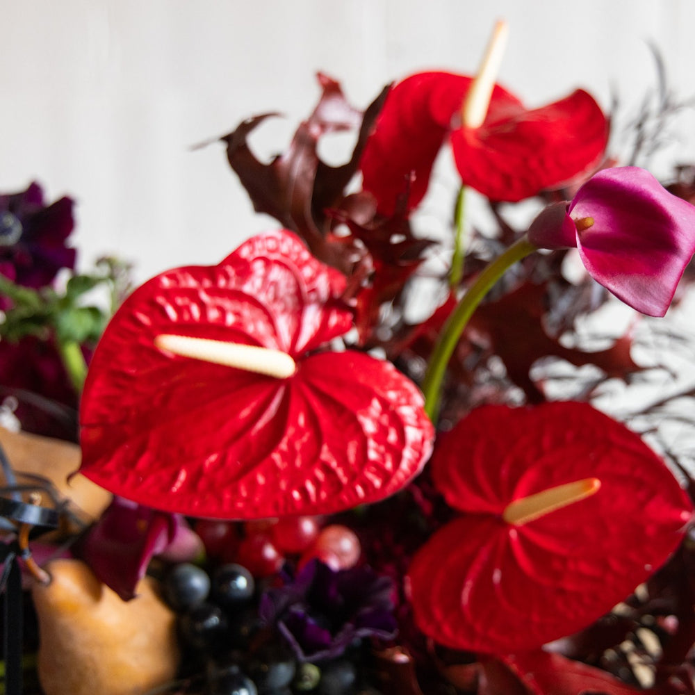 Bouquet of red Anthurium flowers with other plants and berries.