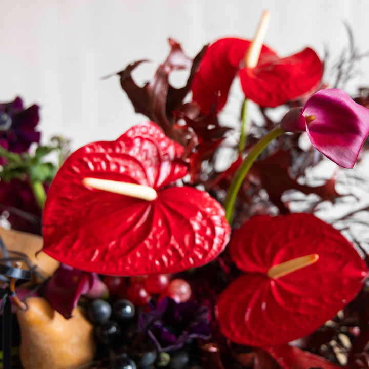 Bouquet of red Anthurium flowers with other plants and berries.
