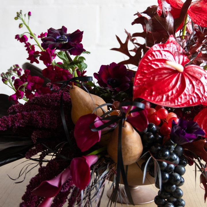 Decorative floral arrangement with red flowers, gourds, and berries on a white background
