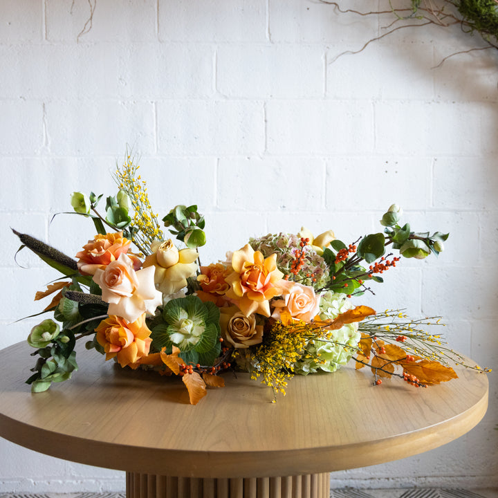 Floral arrangement on a wooden table with a white brick wall background