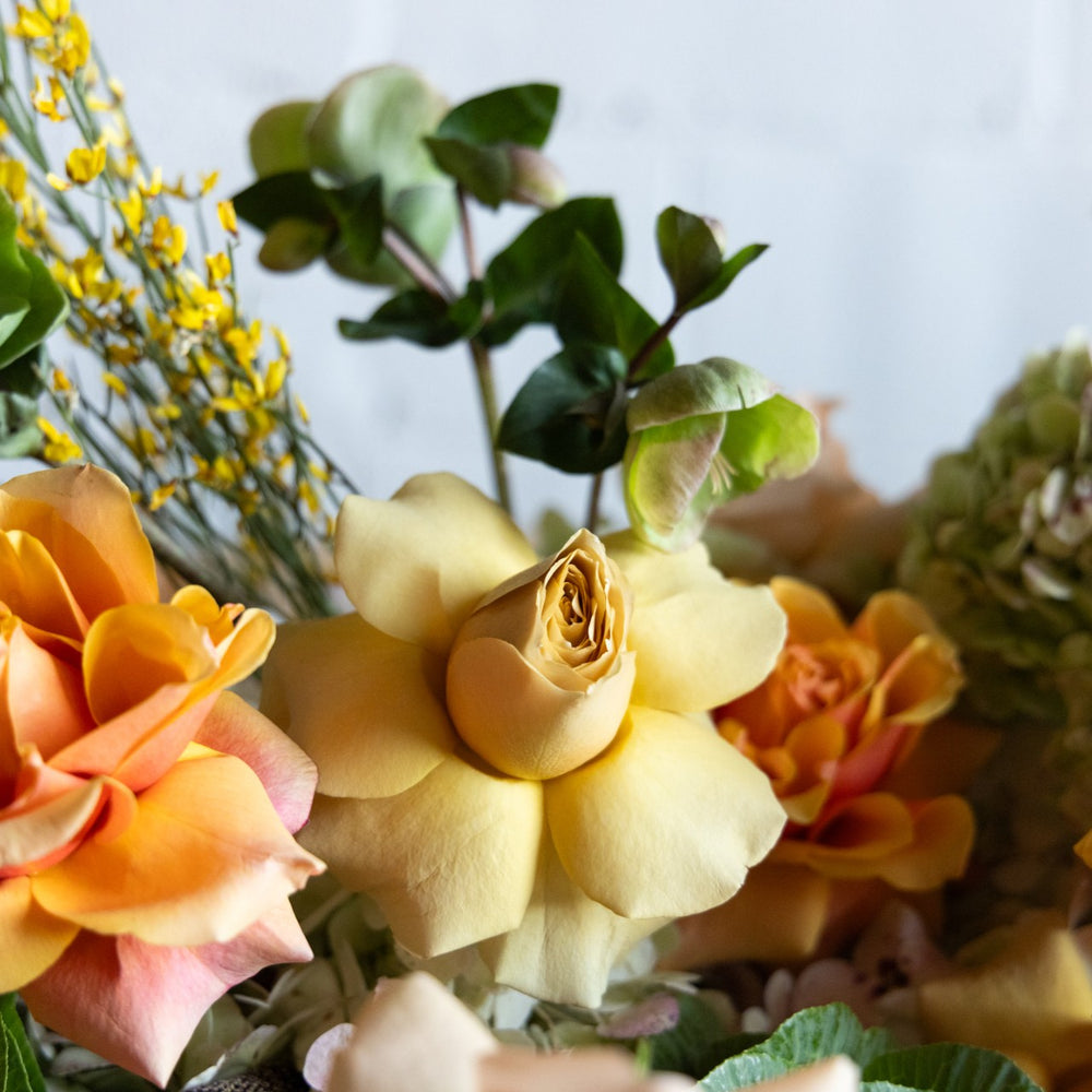 Close-up of a bouquet with yellow and orange flowers and green leaves.