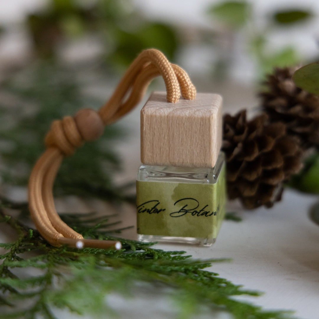 Car air freshener with wooden base and green label on a blurred natural background