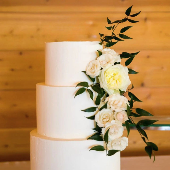 Stacy K Floral | Cake Flowers on a white 3 tiered cake with greenery.