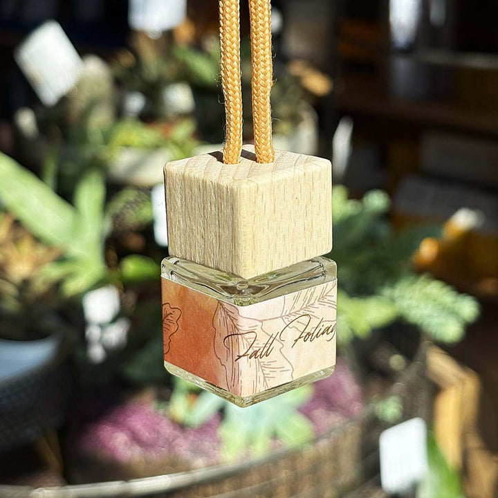 Stacy K Floral | Fleurish Co | Fall Foliage | Square wooden hanging diffuser with a glass container in a blurred indoor setting.