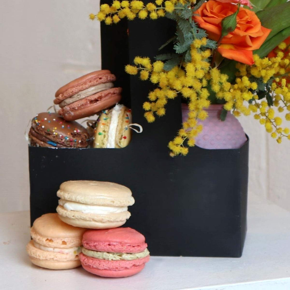 Macaron carrier featuring freshly baked macarons from Scratch Bakeshop on one side and a beautiful floral arrangement from Stacy K on the other