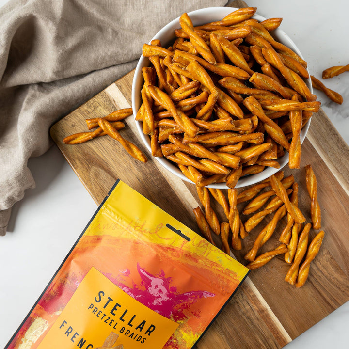 Stellar Pretzel Brads French Dijon packaging with a bowl of pretzels on a wooden board.