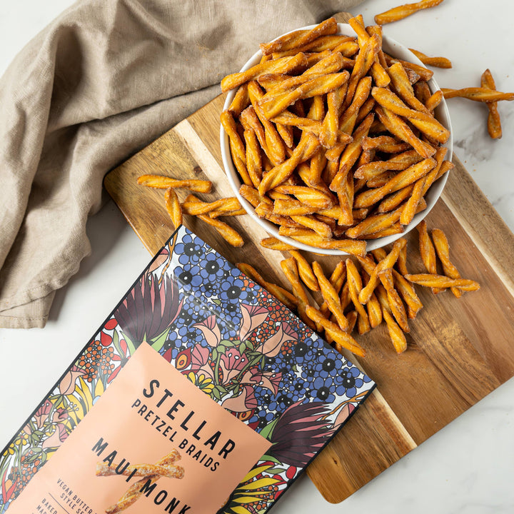 Stellar Pretzel Brands snack sticks on a wooden board with packaging and a napkin.