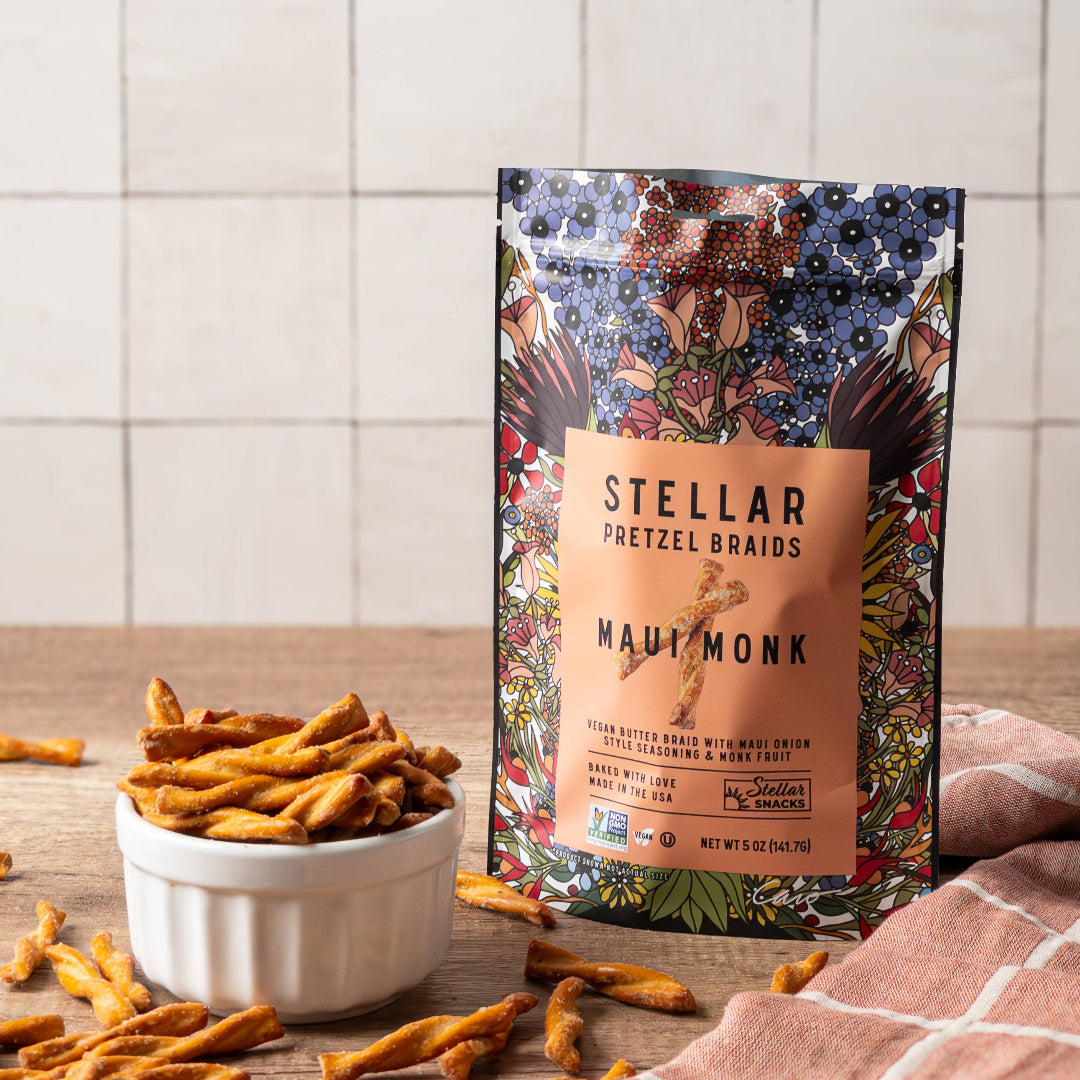 Stellar Pretzel Braids packaging with pretzels on a wooden surface and tiled wall background