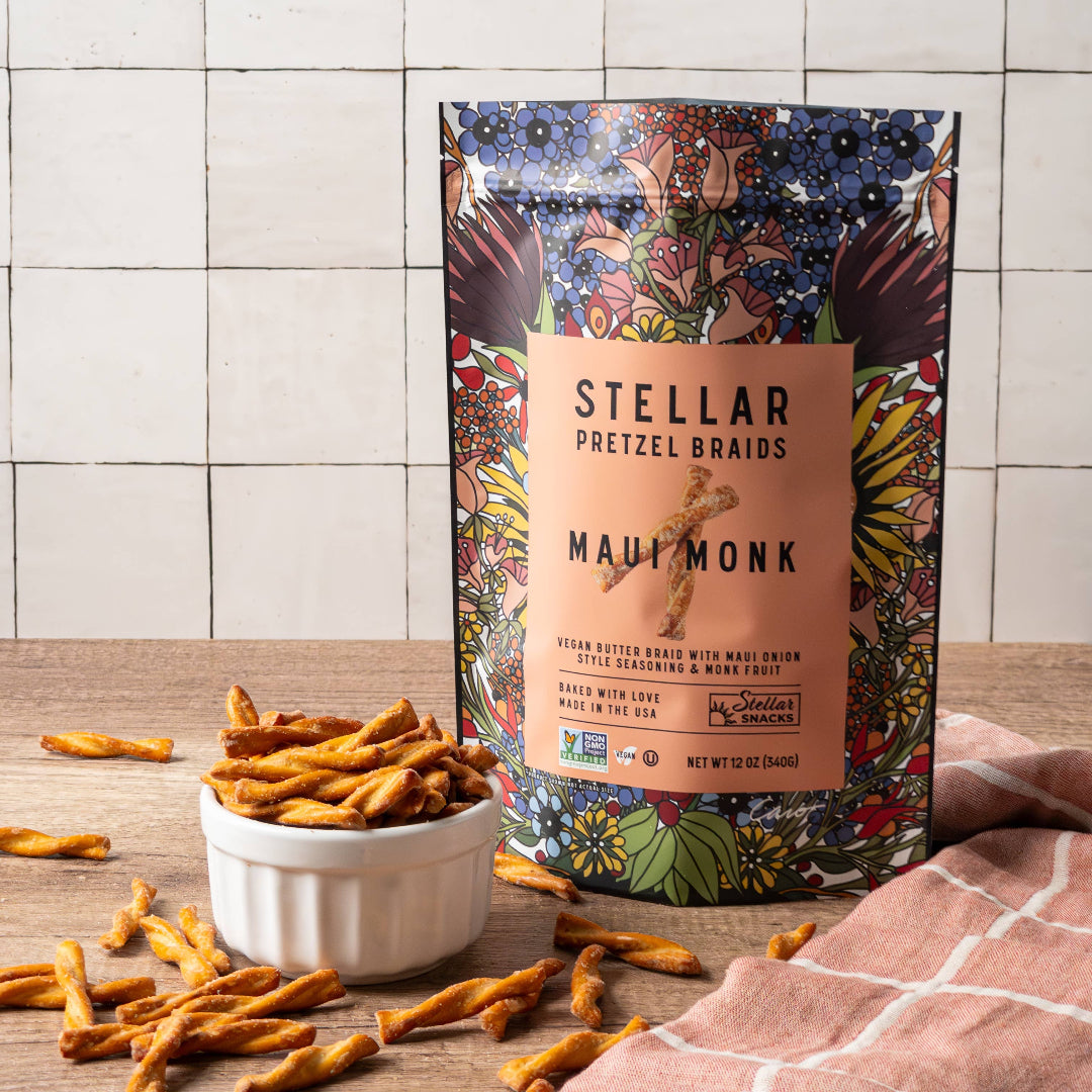 Stellar Pretzel Braids packaging with pretzels on a wooden surface and tiled wall background