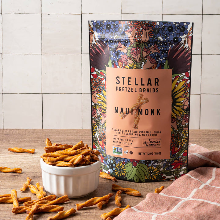 Stellar Pretzel Braids packaging with pretzels on a wooden surface and tiled wall background