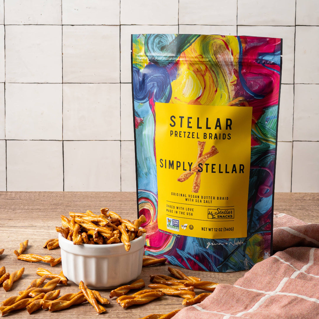 Colorful bag of Simply Stellar pretzel brands on a wooden surface with pretzels around.