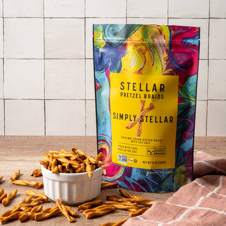 Colorful bag of Simply Stellar pretzel brands on a wooden surface with pretzels around.