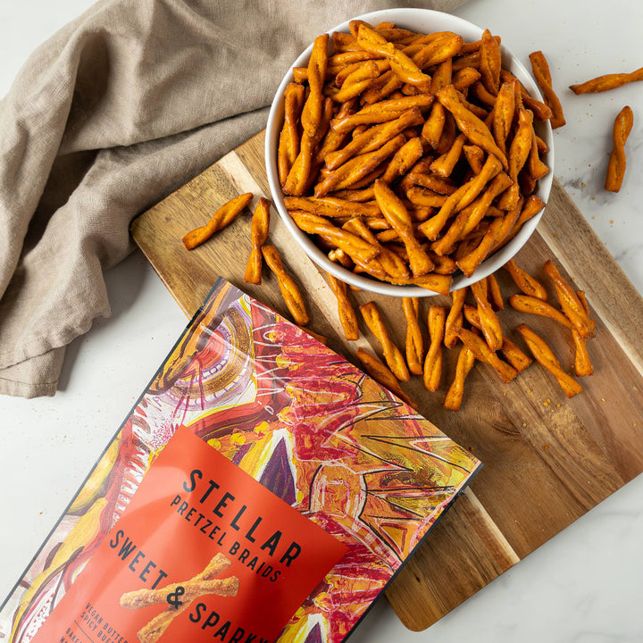 Stellar Sweet &amp; Sparkle pretzel snack on a wooden board with packaging and scattered snacks.