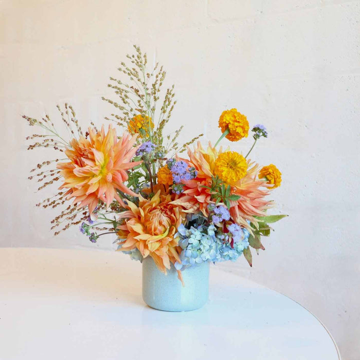 A bright arrangement with hydrangea, mums, grasses, and more.