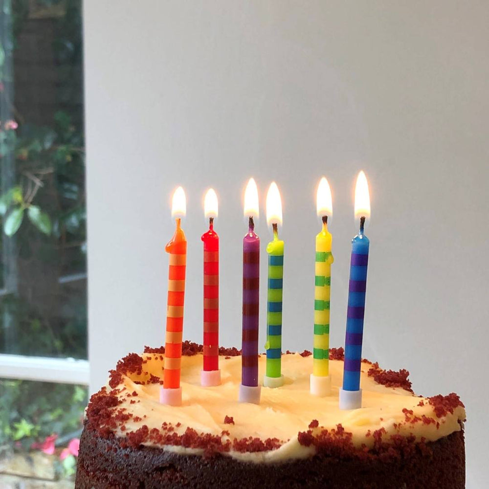 Talking Tables | Chocolate cake with lit colorful candles on a white background