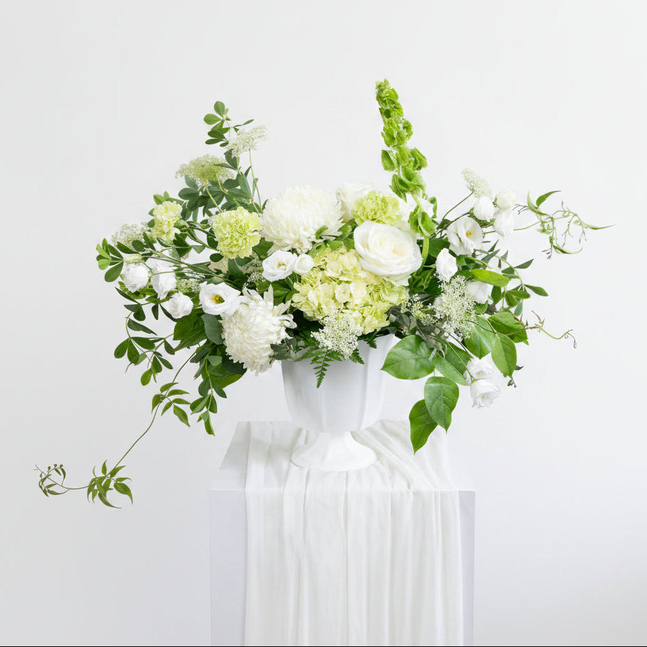 Floral arrangement in a white vase on a wooden surface with a neutral background